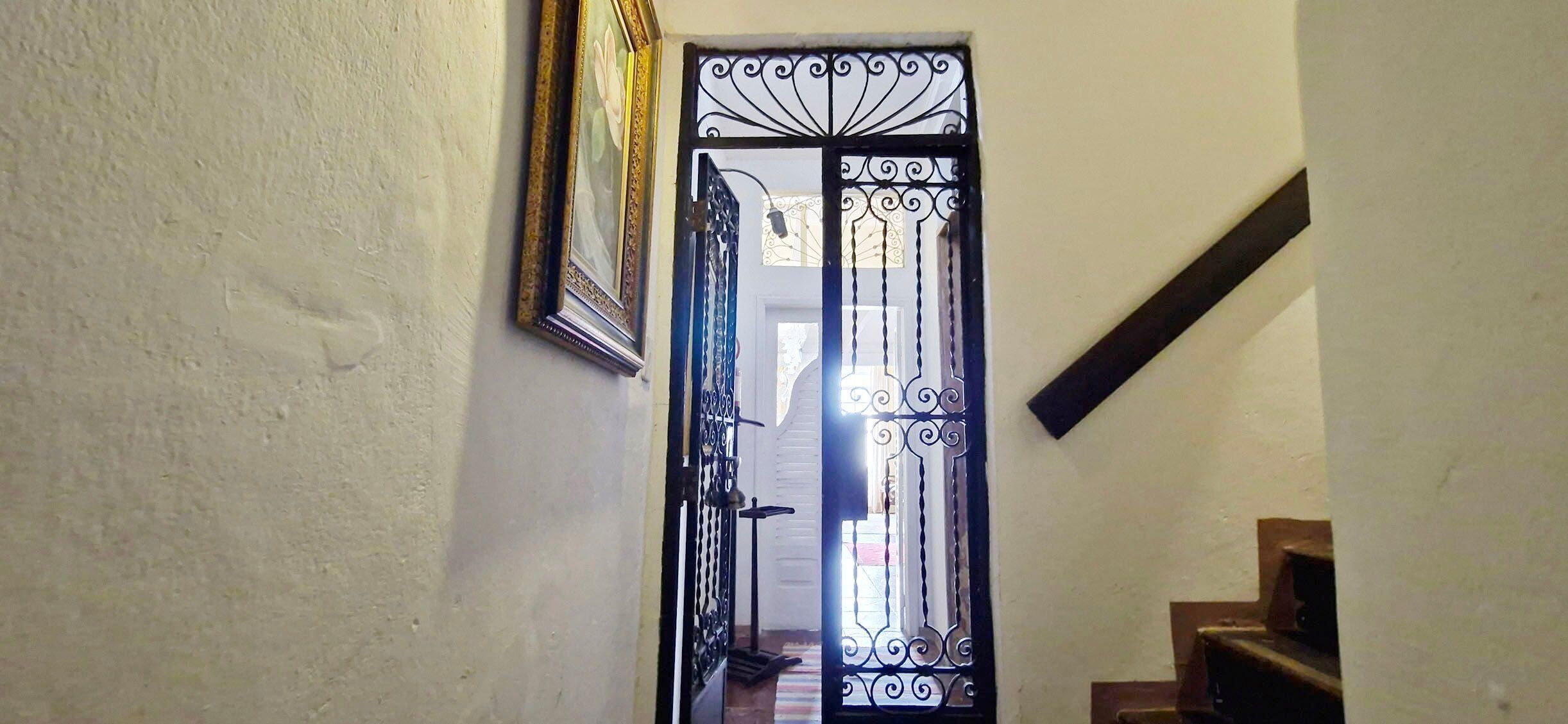 A hallway with a decorative metal gate, a staircase, and a framed picture on the wall.