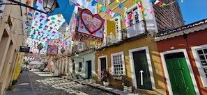 Uma rua estreita com bandeiras coloridas e um letreiro em forma de coração.