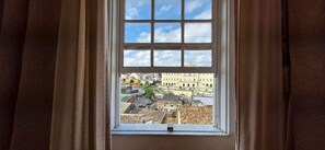Uma janela com vista para a paisagem urbana, cortinas e céu claro.