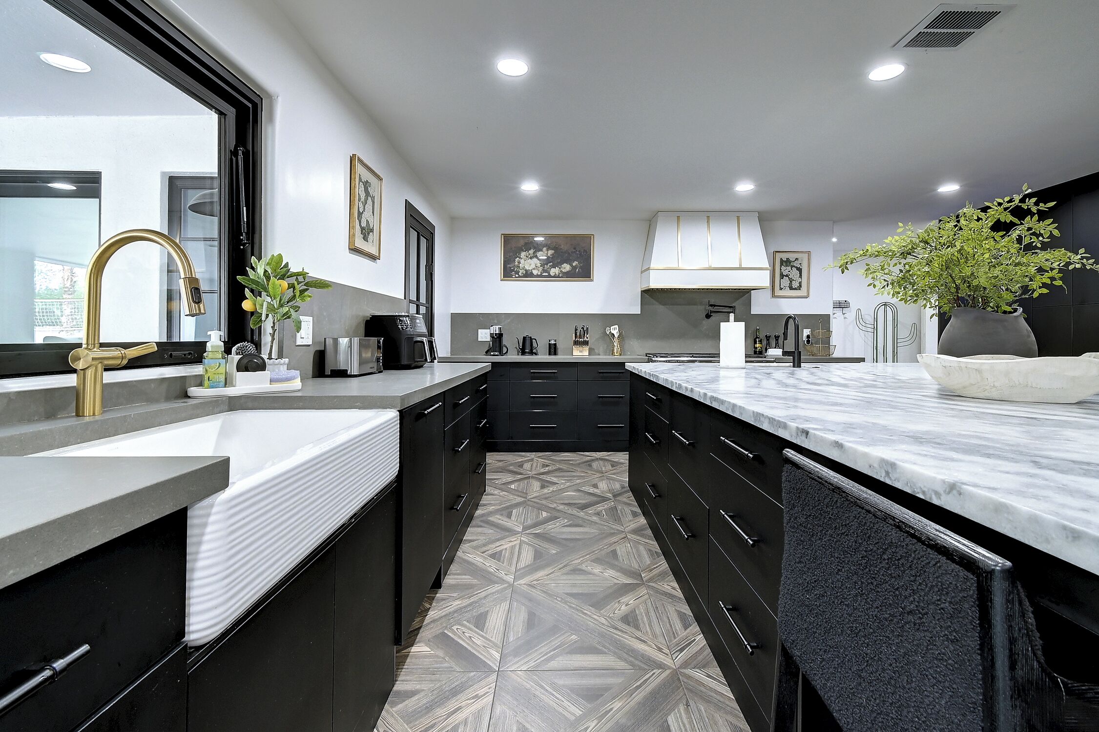 Uma cozinha moderna com uma ilha grande, armários pretos e piso estampado.