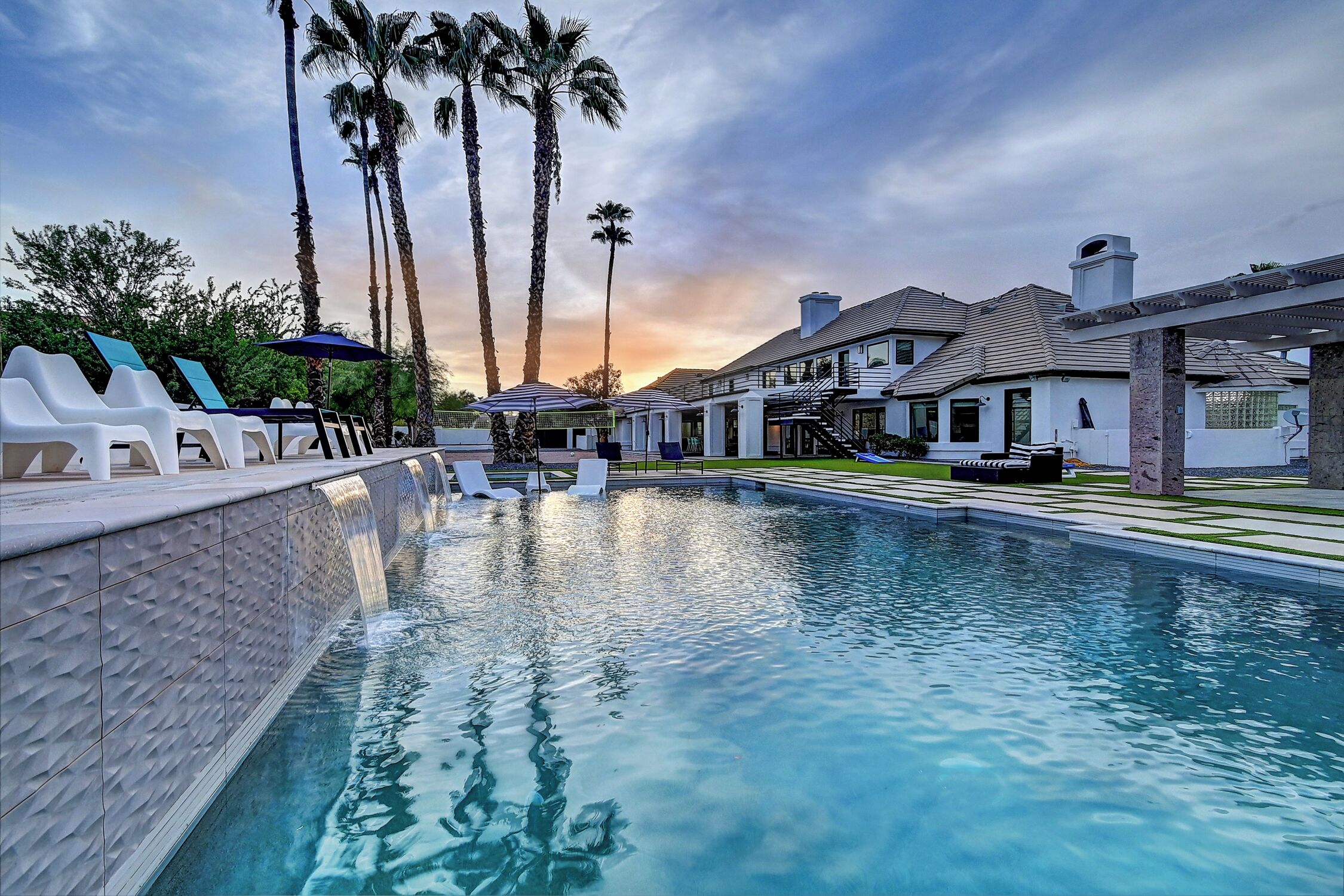 A swimming pool with lounge chairs and palm trees.