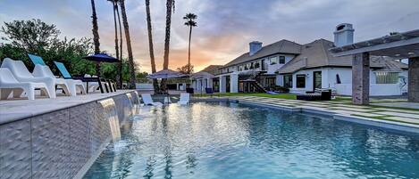A swimming pool with lounge chairs and palm trees.