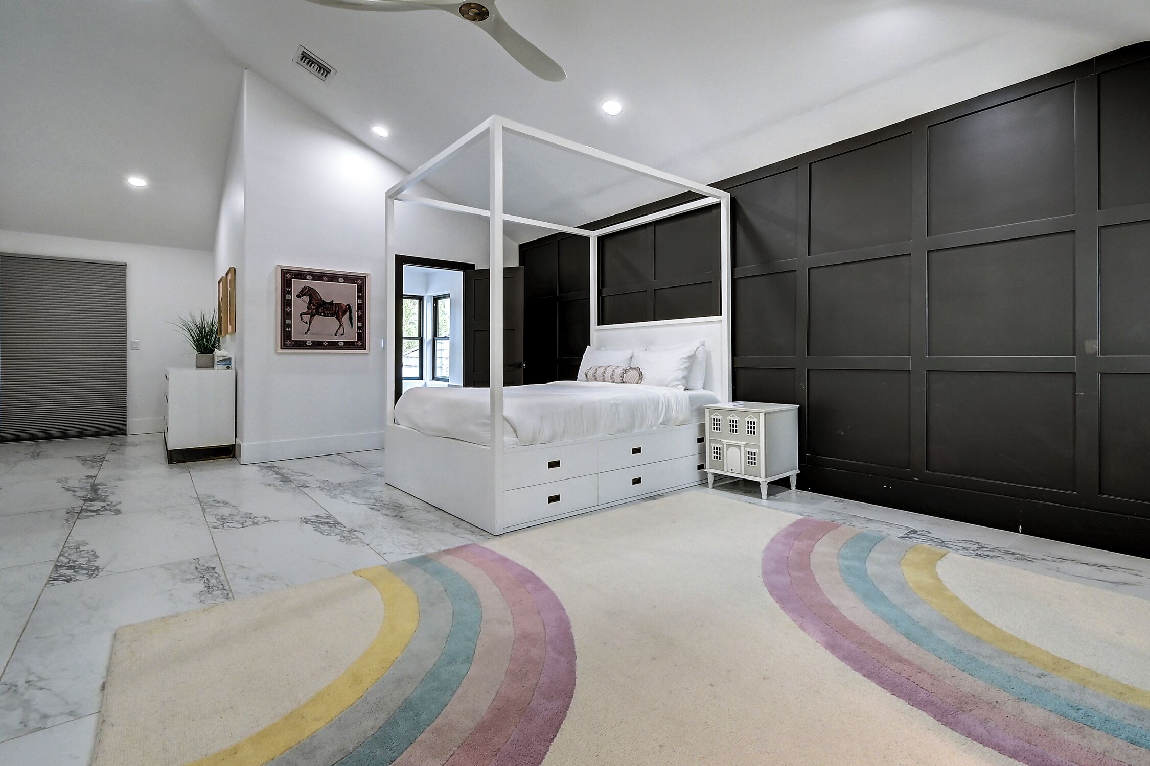 Une chambre à coucher moderne avec un lit à baldaquin, une table de chevet, un grand panneau mural foncé et un sol en marbre.