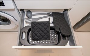 Eine Küchenschublade mit einem schwarzen Pfannenwender, einem schwarzen Utensilienhalter und einem schwarzen Topflappen.