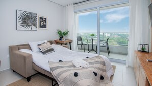 Ein modernes Schlafzimmer mit einem Bett, einem kleinen Tisch mit Pflanze und einem Balkon mit Stühlen.