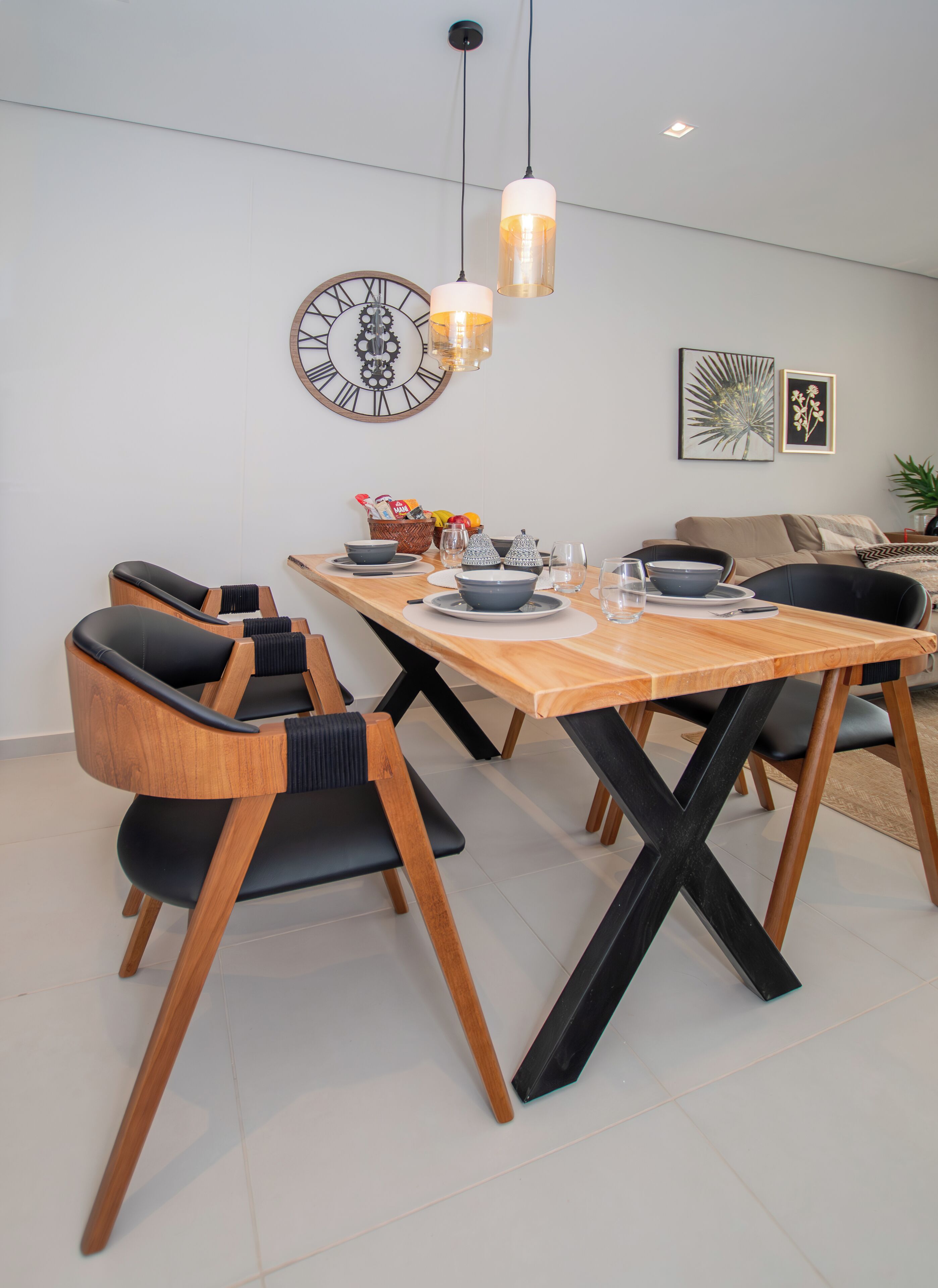 Un comedor con mesa de madera, sillas de madera y color negro, e iluminación colgante.