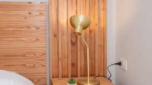 Ein Nachttisch aus Holz mit einer Lampe, einer kleinen Topfpflanze und einem Korb mit Dekoration.