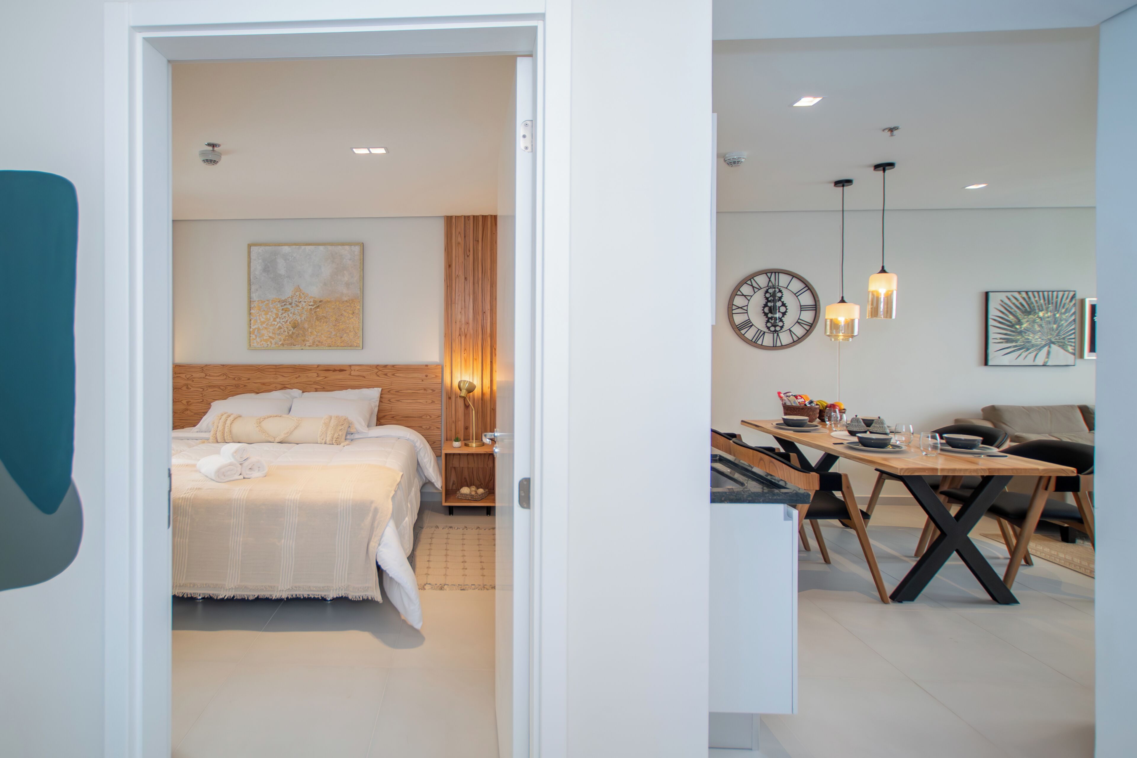 Una habitación de hotel moderna con una cama bien hecha, un cabecero de madera y una mesita de noche con lámpara.