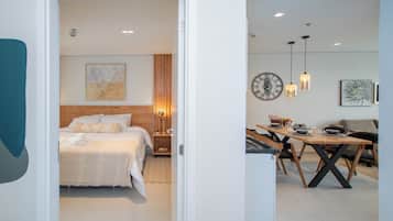 Una habitación de hotel moderna con una cama bien hecha, un cabecero de madera y una mesita de noche con lámpara.