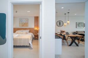 A modern hotel room with a neatly made bed, a wooden headboard, and a bedside table with a lamp. - Corporate Stays First Living - 904 (Asunción)