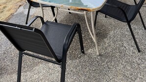 An outdoor patio with a glass table and four chairs, a wooden fence, and a house in the background. - 2 Masters,4 bedrooms total, 2 Kitchens, 3 Living Areas,Hot Tub, Game RM & Gym (Lake Stevens)