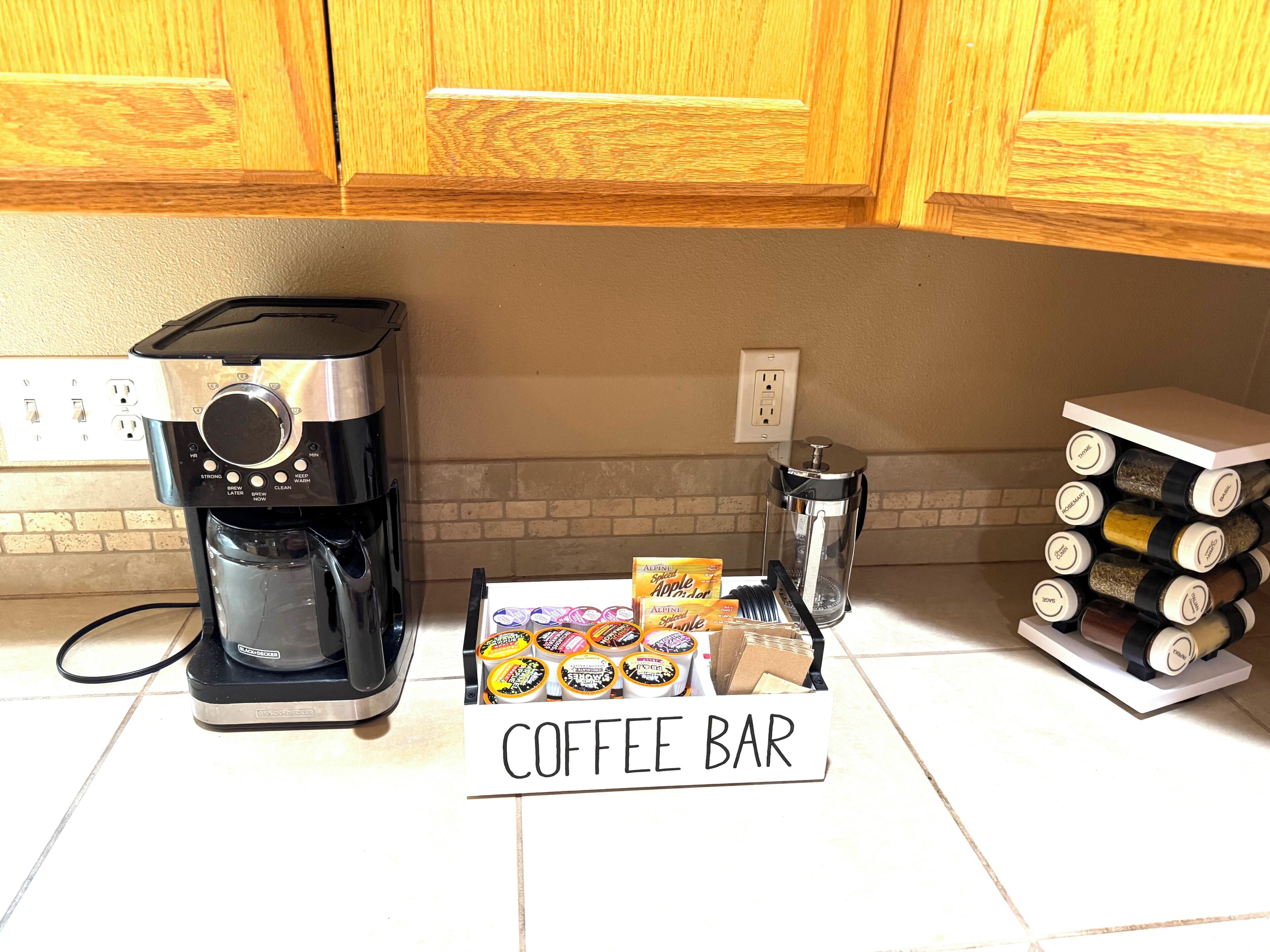 Une cuisine équipée d’une machine à café, d’un panneau indiquant un bar à café et d’un étagère à épices.