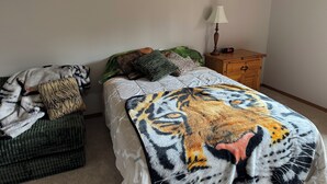 A bedroom with a bed, a nightstand, a lamp, and a blanket with a tiger design. - 2 Masters,4 bedrooms total, 2 Kitchens, 3 Living Areas,Hot Tub, Game RM & Gym (Lake Stevens)