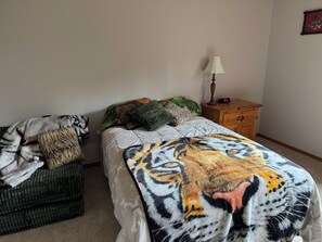 Ein Schlafzimmer mit einem Bett, einem Nachttisch, einer Lampe und einer Decke mit Tiger-Motiv.