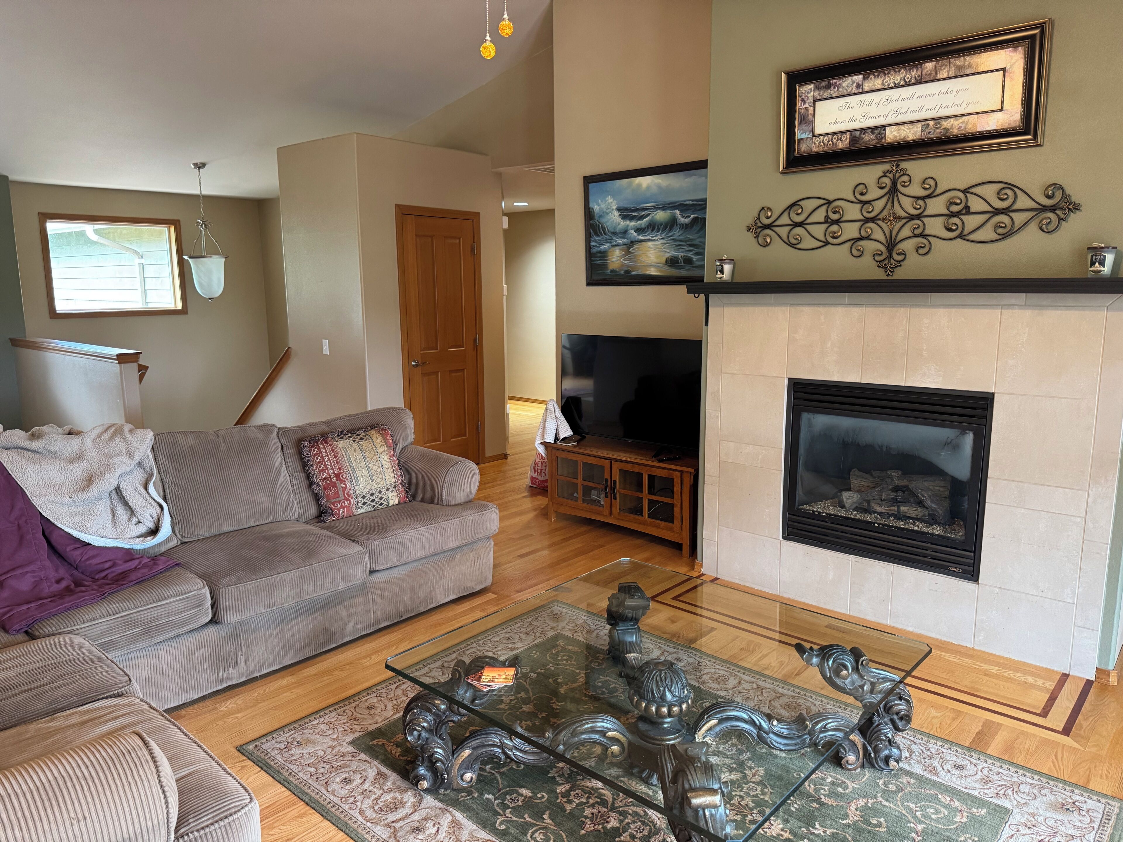 A living room with a sofa, a glass coffee table, a fireplace, and a television.