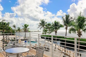 Eine Terrasse mit Pool, Palmen und Blick auf den Ozean.