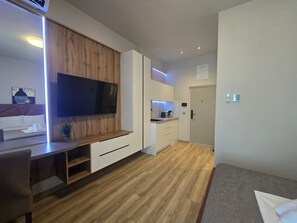Una cocina moderna con televisor integrado, armarios de madera y un pequeño comedor.