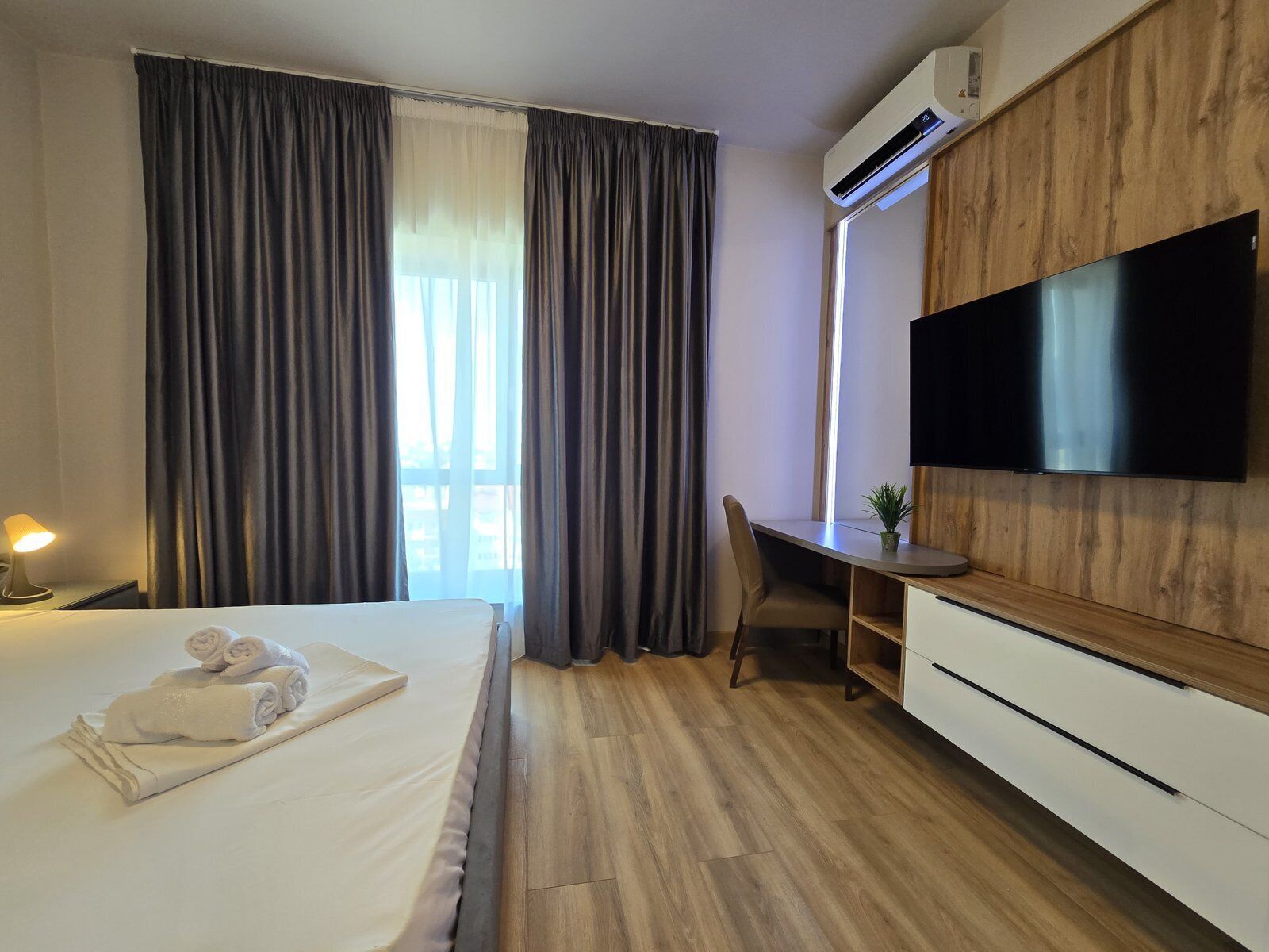 Una camera d'albergo con un letto, una scrivania, un televisore e un condizionatore d'aria.