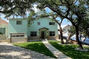 A two-story house with a front porch, a garage, and a well-maintained lawn. - Lake FRONT-3 Story-Sleeps 12-Game FLOOR-Free Kayaks! (Canyon Lake)
