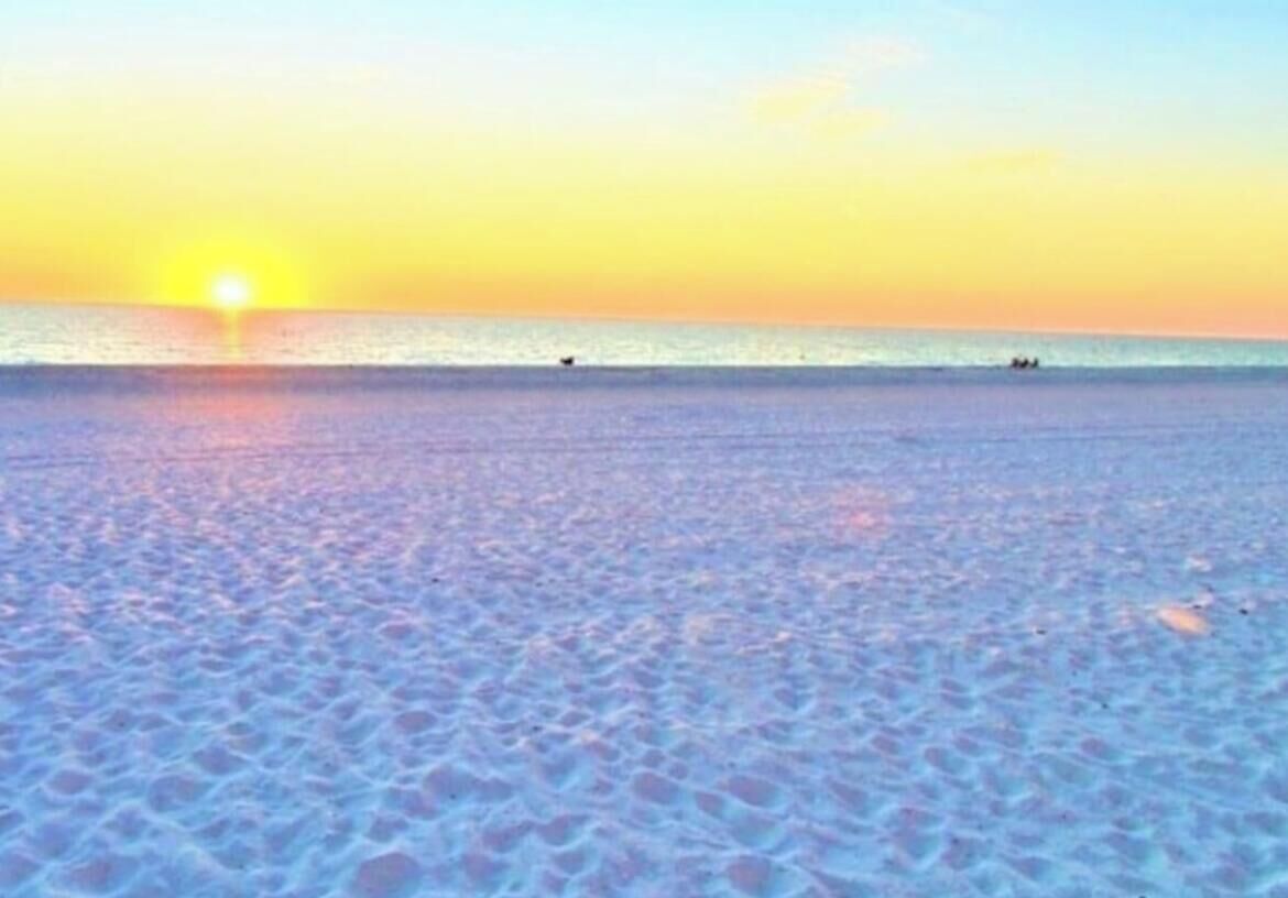 Una playa con un atardecer de fondo.