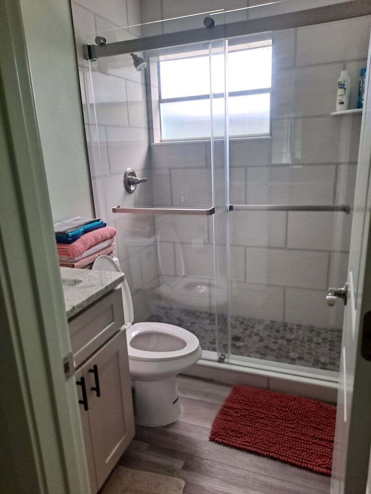 Ein Badezimmer mit Duschkabine, Toilette und Waschbecken mit Ablagefläche.