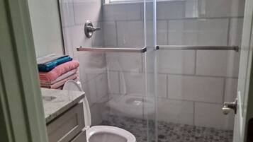 Ein Badezimmer mit Duschkabine, Toilette und Waschbecken mit Ablagefläche.