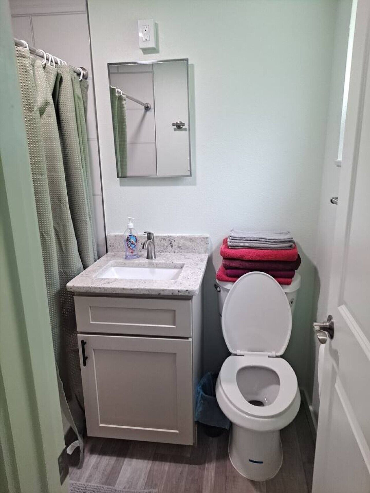A bathroom with a toilet, sink, and mirror.