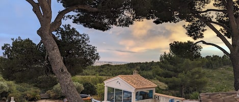 A modern villa with a swimming pool, a small detached structure, and a view of a cityscape.