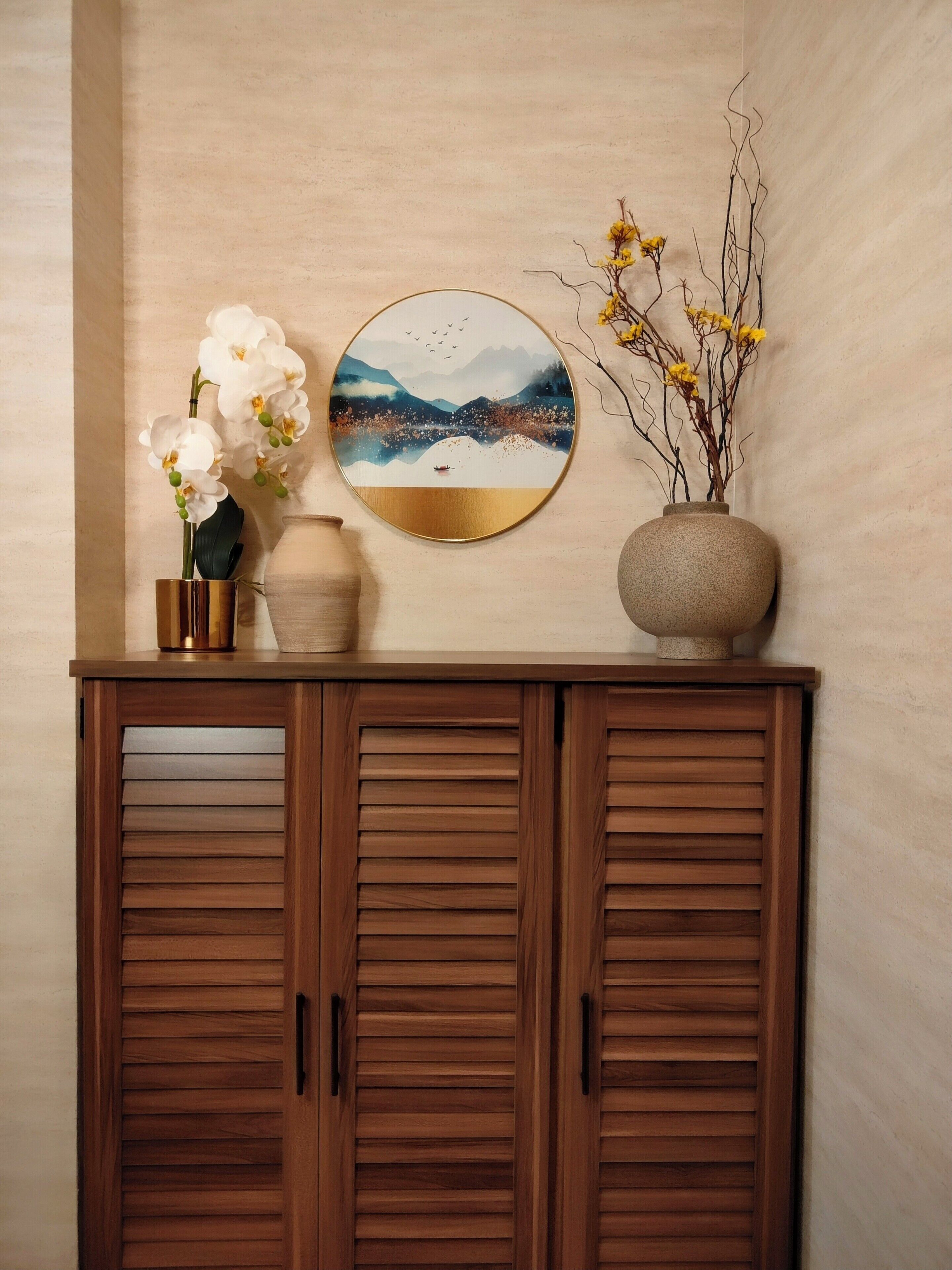 A wooden cabinet with a round wall art piece above it.