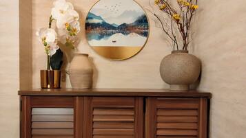 A wooden cabinet with a round wall art piece above it.