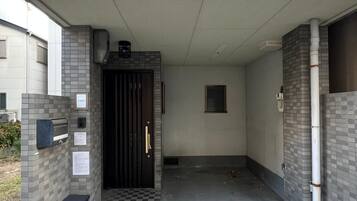 A covered entrance with a checkered floor, a door, and a trash bin.