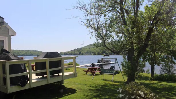 En badebro ved søen med grill, picnicbord og gyngestativ.