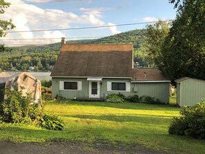 Ein eingeschossiges Haus mit Satteldach, einer Veranda und einer kleinen angeschlossenen Garage.