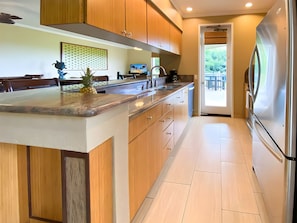 A modern kitchen with wooden cabinets, a granite countertop, and a stainless steel refrigerator. - Wailea, Grand Champions Villas, Spacious 6 BR, Ocean View, Sleeps 16 (Wailea)