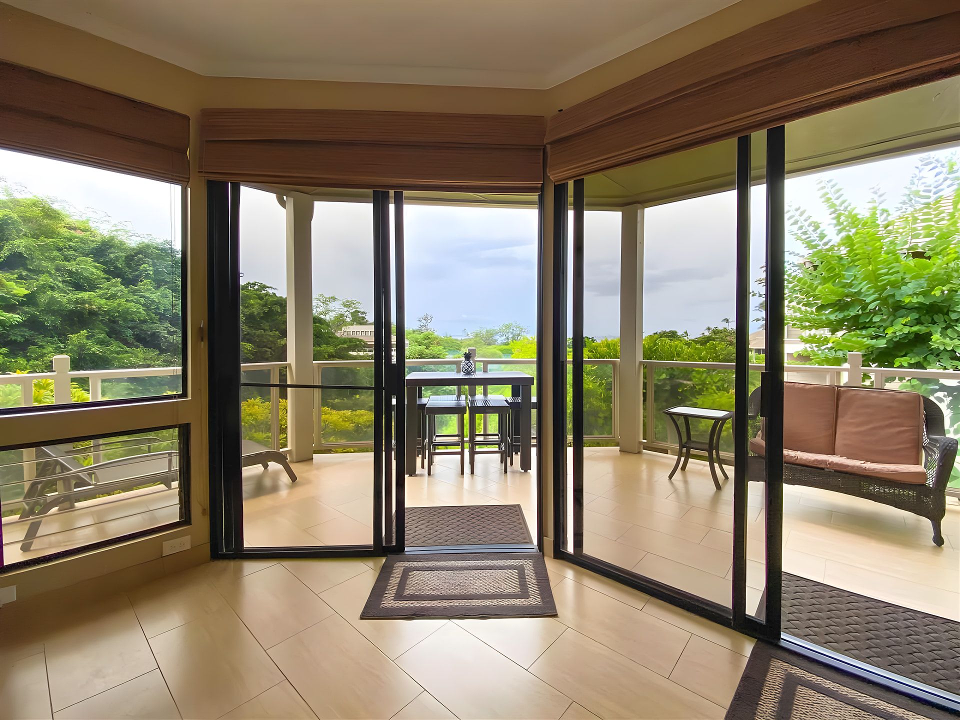 A room with a glass door leading to an outdoor patio with a table and chairs.