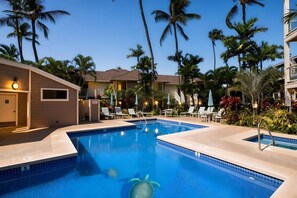 A swimming pool with lounge chairs and palm trees, surrounded by hotel buildings. - Ocean View 6BR, 2 Condos for 16 in Wailea, Hawaii! (Wailea)