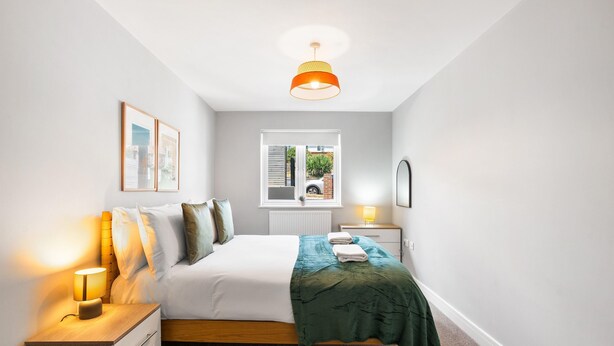 A bedroom with a bed, bedside tables, a window, and a hanging light fixture. - Woodland View 1 By My Getaways (Brighton)