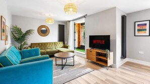 A modern living room with a sectional sofa, a coffee table, a flat-screen TV, and a large window. - Woodland View 1 By My Getaways (Brighton)