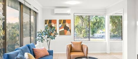 A modern living room with a blue sofa, a brown leather chair, a round coffee table, and artwork on the walls.