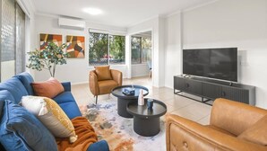 A modern living room with a sofa, armchair, coffee table, and a flat-screen TV. - Heart of Sunnybank | Prime Location | Great Value (Sunnybank)