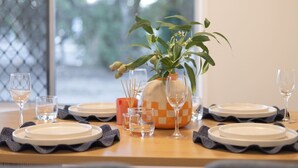 A dining table set with plates, glasses, and a vase with a plant. - Heart of Sunnybank | Prime Location | Great Value (Sunnybank)