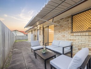 Une terrasse avec un ensemble de meubles de salon, une table basse et un mur en briques.