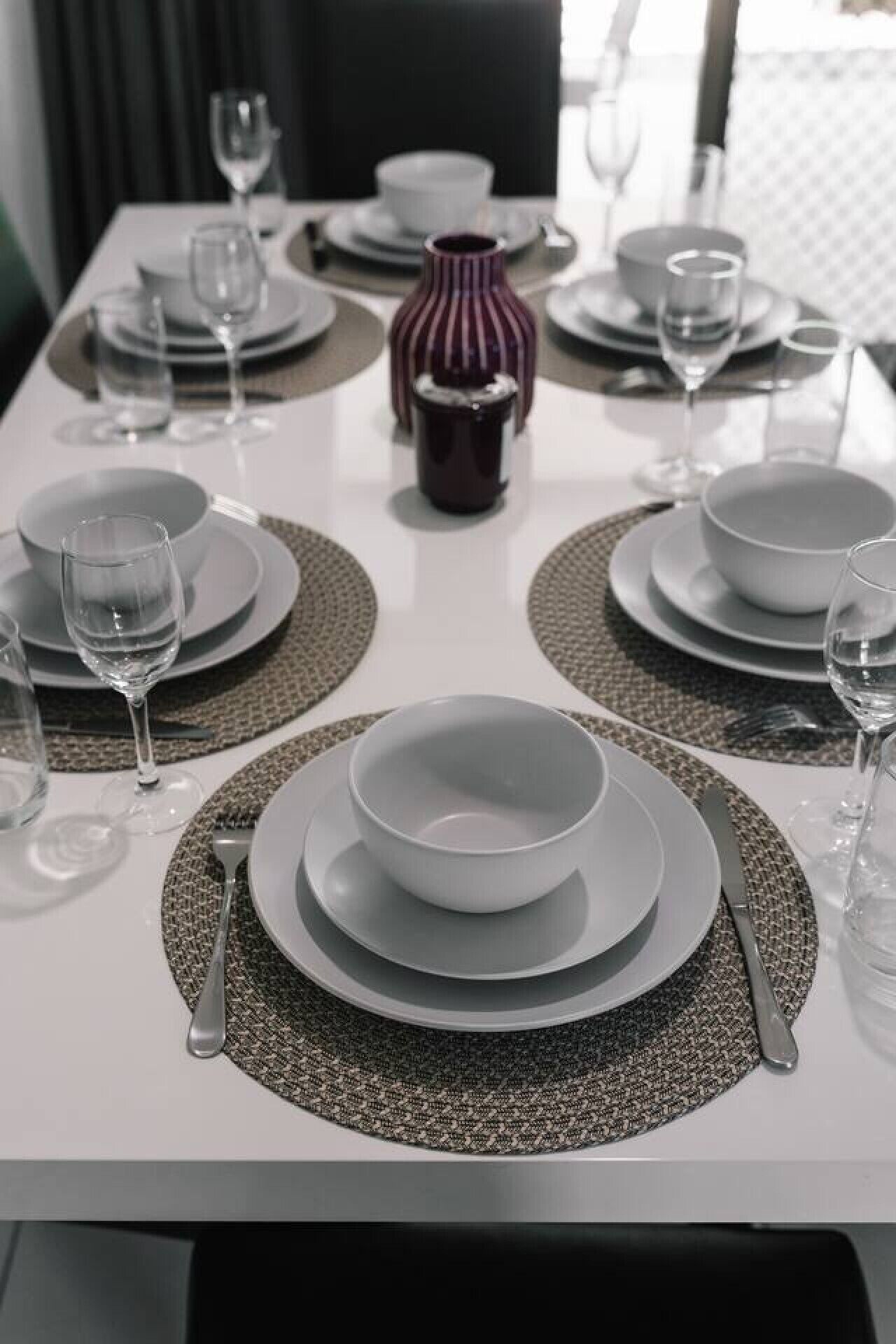 A dining table set with plates, bowls, glasses, and cutlery.