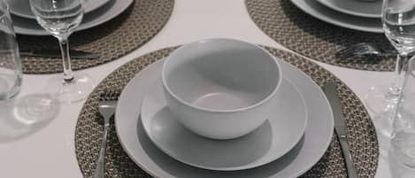 A dining table set with plates, bowls, glasses, and cutlery.
