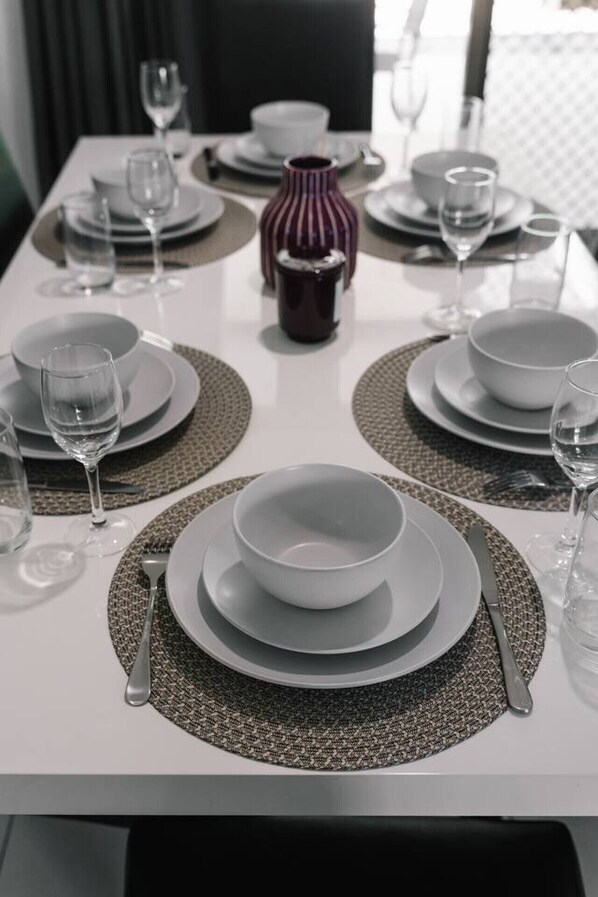 A dining table set with plates, bowls, glasses, and cutlery.