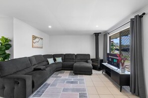 A modern living room with a sectional sofa, a fireplace, and a large window with curtains.