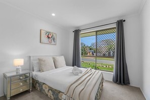 A bedroom with a bed, bedside table, and a window with curtains.