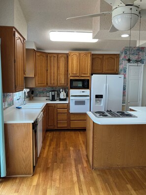 A kitchen with wooden cabinets, a microwave, a stove, and a refrigerator.