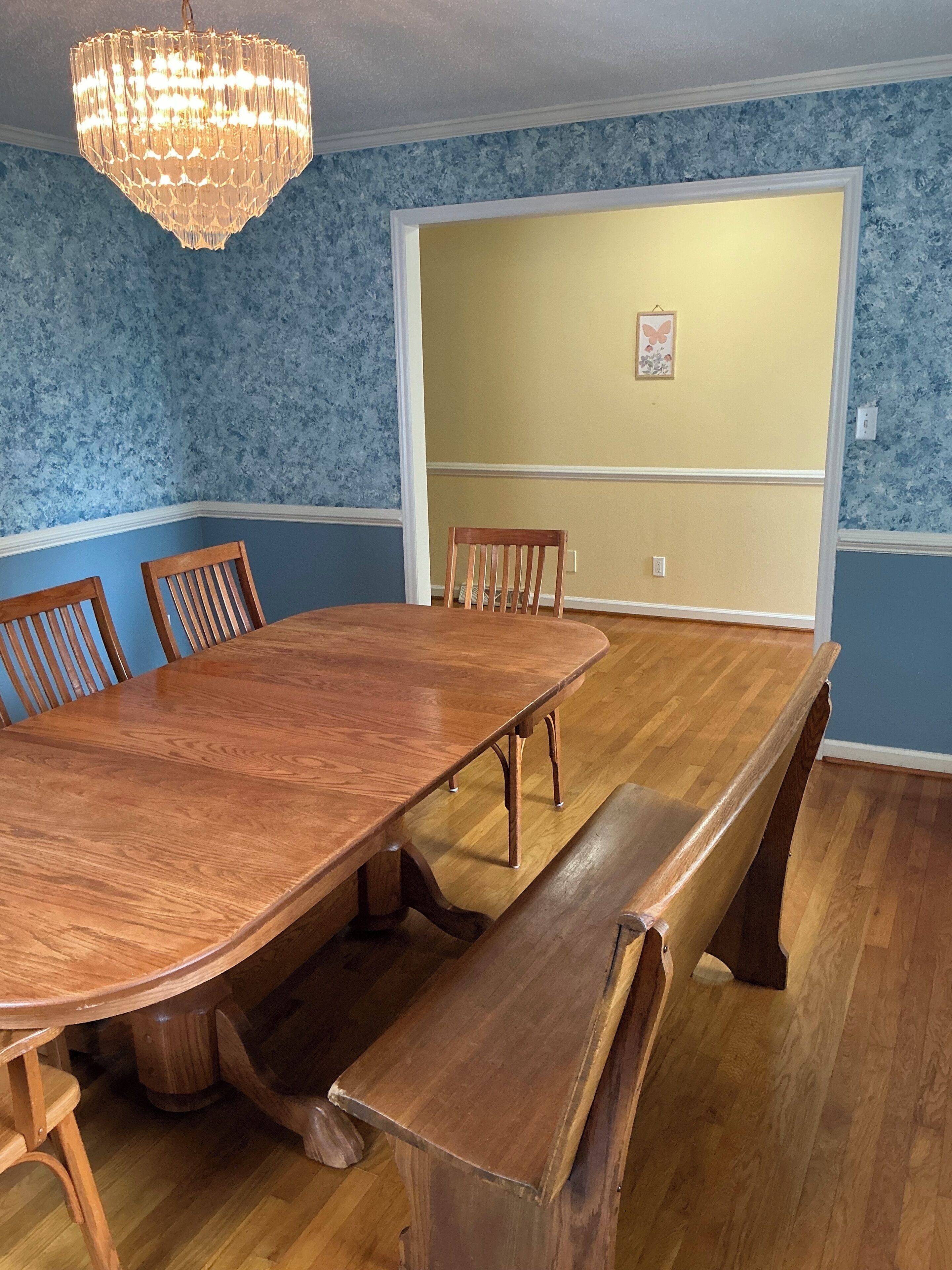 A dining room with a large wooden table, benches, and chairs.