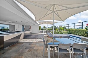 An outdoor kitchen area with a bar, seating, and a pool. - Surfers Paradise Escape| carpark|Resort Facilities (Surfers Paradise)